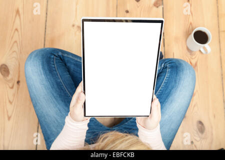 La donna la lettura su tablet con pavimento in legno Foto Stock