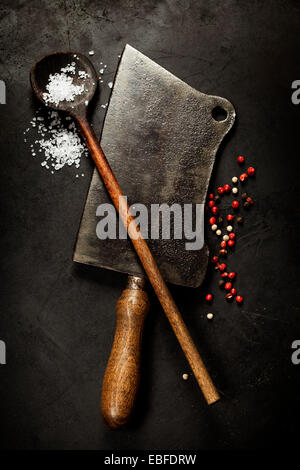 Vecchio cucchiaio di legno e carne cleaver coltello su sfondo scuro Foto Stock