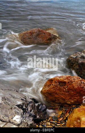 Mare di vorticazione su rocky groyne Foto Stock