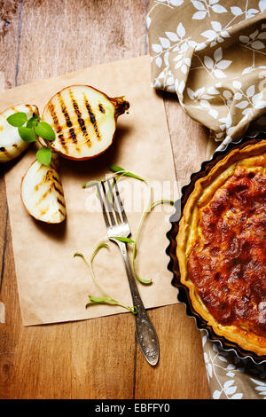 Torta di cipolle servito con grigliate di cipolla e erbe aromatiche fresche. Stile rustico. Vista dall'alto. Foto Stock