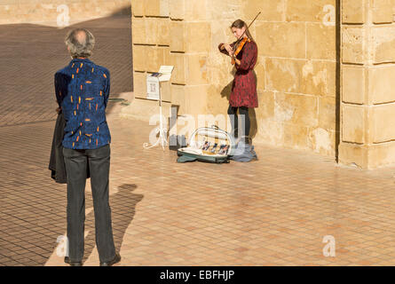 CORDOBA SPAGNA ragazza giovane la riproduzione di un violino SUL PONTE ROMANO GATEWAY [ Puerta del Puente ] ascoltato da uno spettatore Foto Stock