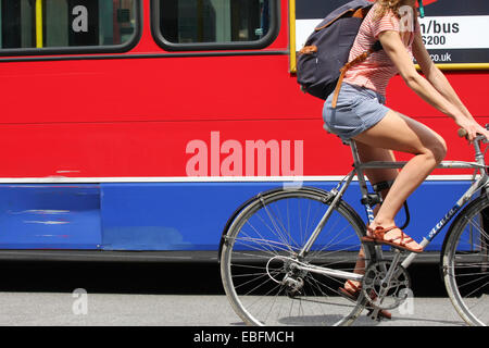 Una femmina di ciclista il sorpasso di un rosso fisso London bus Foto Stock