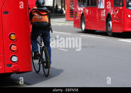 Un ciclista il sorpasso di un rosso fisso London bus Foto Stock