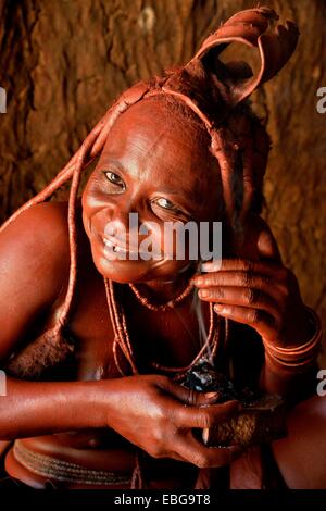 Tradizionalmente condita Himba donna nel suo rifugio, applicazione di profumo, Purros villaggio tradizionale, Purros, Kaokoland, Kunene, Namibia Foto Stock