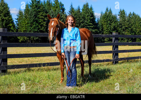 41,857.09282 ragazza adolescente in blu in piedi da & holding una baia a cavallo Foto Stock