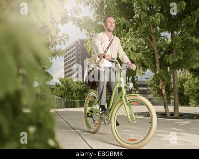 Uomo che porta un sacchetto sopra la sua spalla mentre in bicicletta nel parco, Innsbruck, in Tirolo, Austria Foto Stock