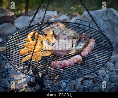 Carne e salumi cotti su una griglia appeso su catene Foto Stock