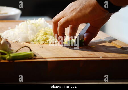 Mano dello chef sul tagliere tritare un pezzo di finocchio Foto Stock