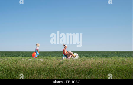 Ragazza adolescente triciclo di equitazione e ragazzo sulla tramoggia gonfiabile Foto Stock