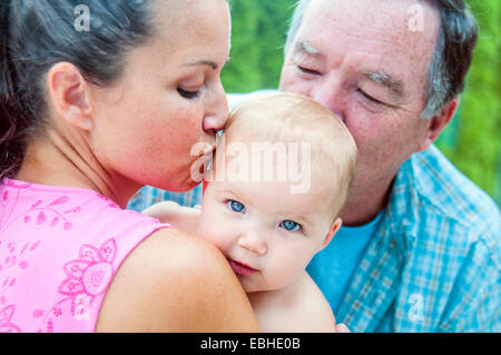 Close up della madre e del nonno kissing Baby girl Foto Stock