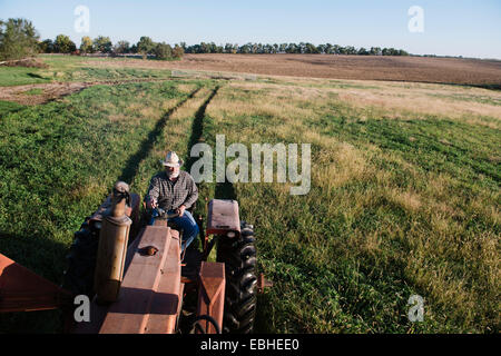 Angolo di Alta Vista del maschio anziano contadino di guidare il trattore nel campo, Plattsburg, Missouri, Stati Uniti d'America Foto Stock