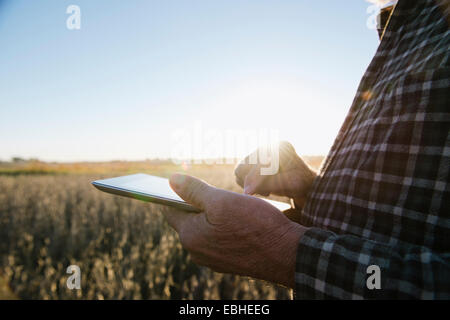 Ritagliato colpo di senior agricoltore maschio utilizzando tavoletta digitale nel campo di soia, Plattsburg, Missouri, Stati Uniti d'America Foto Stock