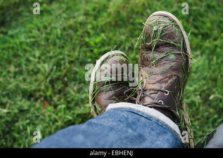Mans calzature contemplate nella fresca di erba falciata Foto Stock