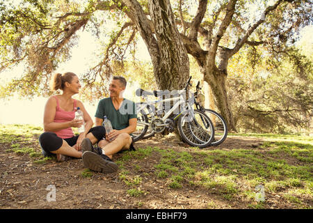 Coppia ciclista giovane prendendo una pausa di acqua in posizione di parcheggio Foto Stock