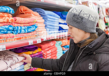 Giovane donna scelta di asciugamani da bagno a shopping nel supermercato Magnit store. Foto Stock