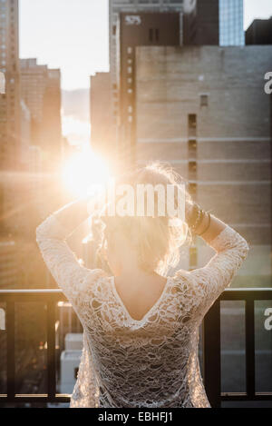 Giovane donna con le mani nei capelli in presenza di luce solare Foto Stock