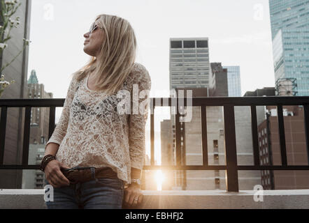 Giovane donna che guarda lontano con la città in background Foto Stock