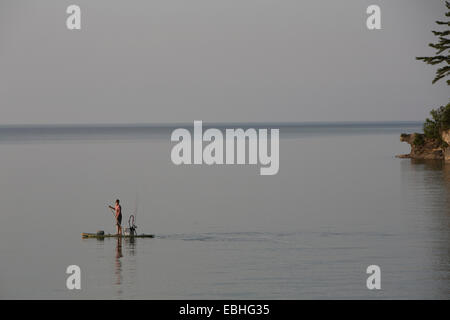 Vista in lontananza ragazzo adolescente la pesca da paddleboard nel Lago Superiore, Au treno Bay, Michigan, Stati Uniti d'America Foto Stock