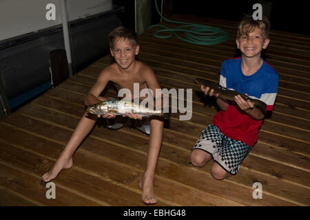 Due fratelli sul molo di notte tenendo lanzardi pesce, Shalimar, Florida, Stati Uniti d'America Foto Stock