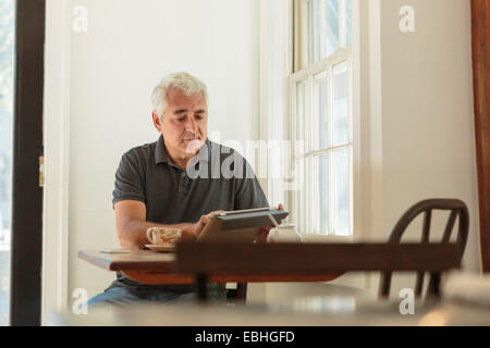 Uomo maturo con tavoletta digitale nel paese store cafe Foto Stock