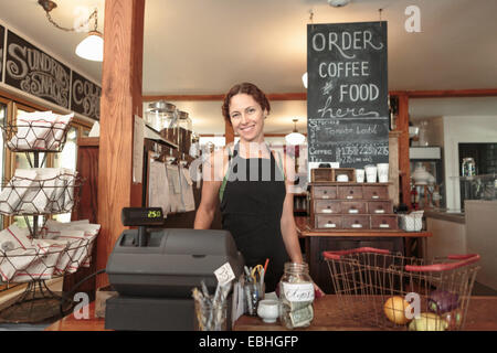 Femmina assistente di vendita controllo fuori shopping in paese store cafe Foto Stock