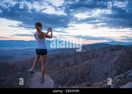 Donna prendendo foto di montagna, Joshua Tree National Park, California, US Foto Stock