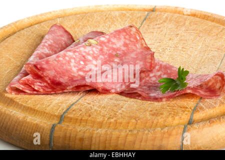 Fette di salame e prezzemolo sulla tavola di legno Foto Stock