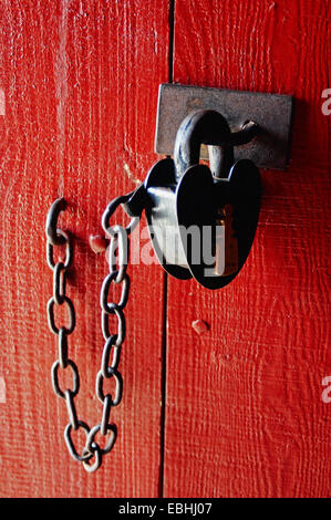 Cuore a forma di lucchetto su un rosso porta in legno Foto Stock