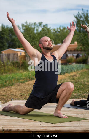 Giovane uomo caucasico praticando yoga outdoor indossando un serbatoio nero top Foto Stock