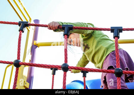 Ragazza giovane di quattro giocando su un Jungle Jim Foto Stock