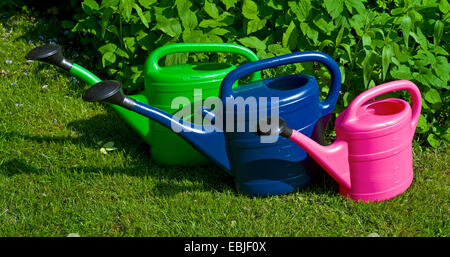 Tre impianti di irrigazione in plastica lattine in piedi a fianco a fianco su un giardino prato, Germania Foto Stock