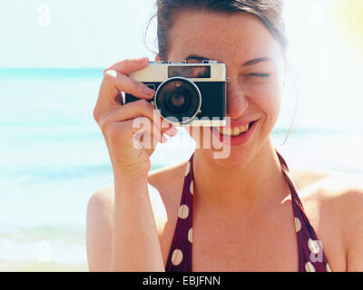 Giovane donna utilizzando la fotocamera sulla spiaggia Foto Stock