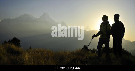 Sagome di due escursionisti di montagna di fronte al sole che sorge sulla collina di Poon presso il massiccio di Annapurna, Nepal Foto Stock
