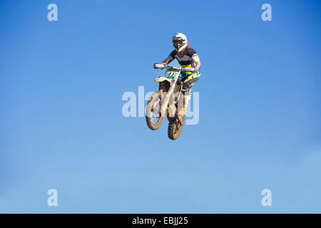 Giovane maschio motocross racer jumping metà aria contro il cielo blu Foto Stock