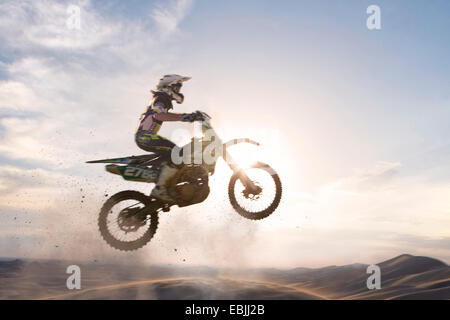 Stagliano giovane maschio motocross racer saltando su traccia di fango Foto Stock