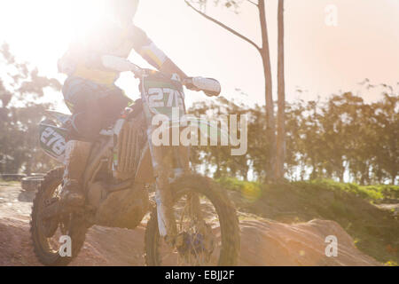 Ritagliato colpo di giovane maschio motocross racer jumping metà di aria verso il basso la collina di fango Foto Stock