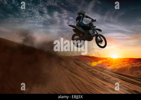 Giovane maschio motocross racer jumping metà aria al tramonto Foto Stock