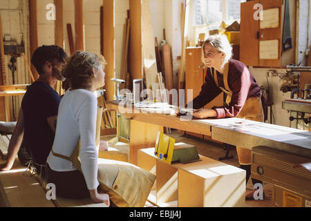 Tre artigiani avente un incontro informale in organo a canne workshop Foto Stock