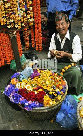 L'uomo la preparazione di ghirlande di fiori di fiori per una cerimonia, Nepal, Kathmandu Foto Stock