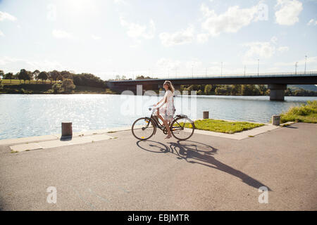 Giovane donna in bicicletta al Riverside, Isola del Danubio, Vienna, Austria Foto Stock