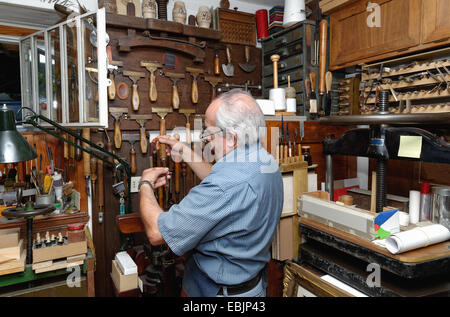 Senior uomo strumenti di selezione in un tradizionale laboratorio di rilegatura di libri Foto Stock