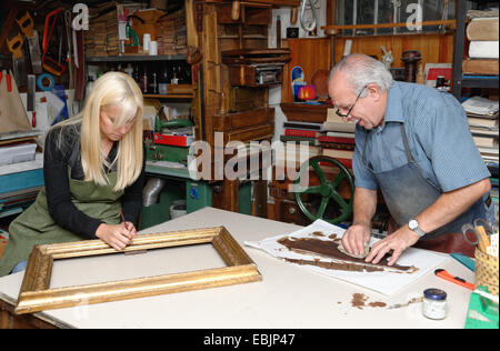 Senior l uomo e la donna giovane ripristino picture frame e del dorso in un tradizionale laboratorio di rilegatura di libri Foto Stock