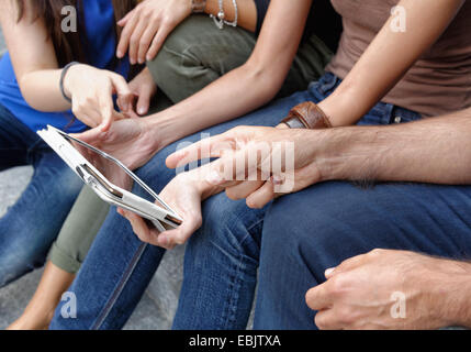 Gruppo di amici alla ricerca a tavoletta digitale, focus su tablet e mani Foto Stock