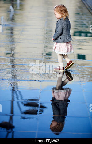 Bambina in mirroring su piastrelle bagnate Foto Stock