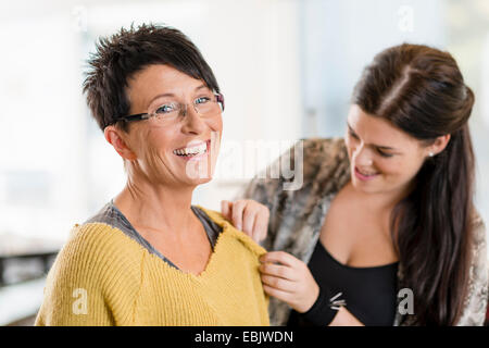 Giovane sarta pinning spalla di clienti maglione in officina Foto Stock