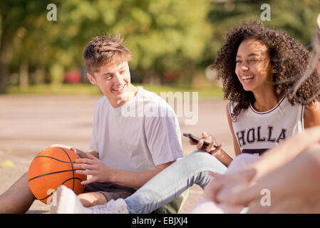 Gruppo di adulti giovani giocatori di basket seduta in chat Foto Stock