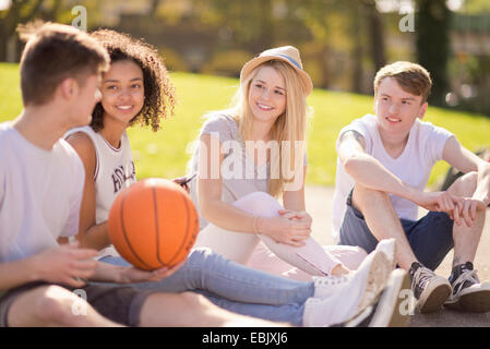 Quattro adulti giovani giocatori di basket seduta in chat Foto Stock