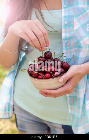 Close up della giovane donna con coppa di ciliegie Foto Stock