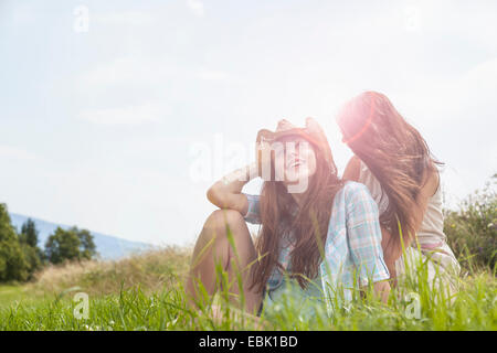 Due giovani donne sedute in chat in campo erboso Foto Stock