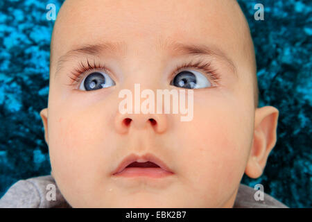 Ritratto di un bambino sdraiato su un cuscino di velluto essendo wide-eyed Foto Stock